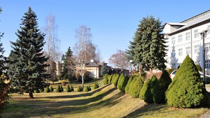 Na zdjęciu widać ogród (trawnik i drzewa), w oddali widać budynki kompleksu DPR Słoneczne Wzgórze