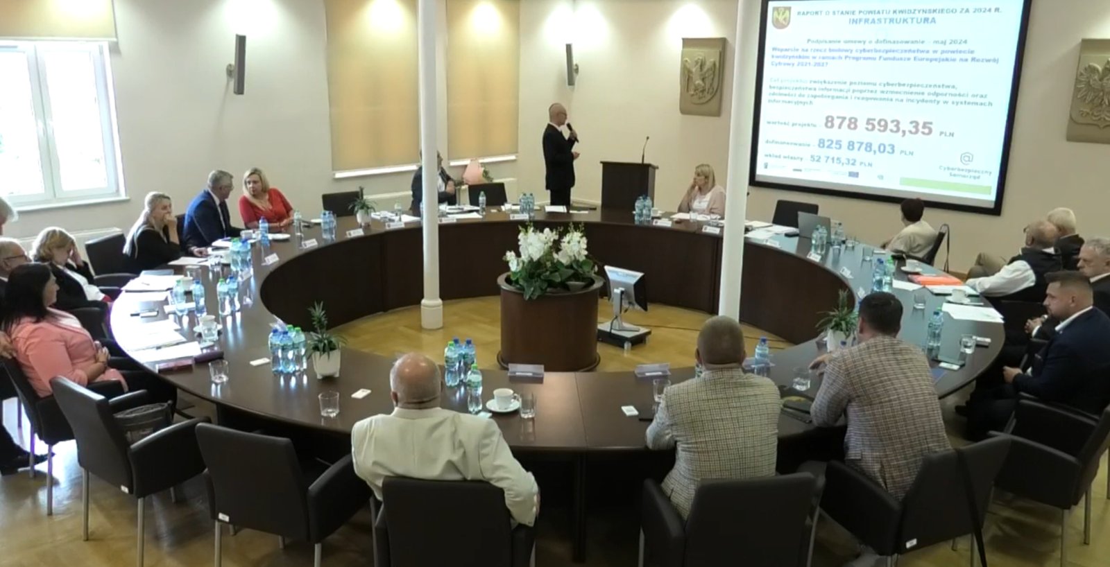 Prezentacja projektu z dofinansowaniem unijnym przedstawiająca salę obrad Rady Powiatu Kwidzyńskiego z osobami uczestniczącymi w obradach i prezentującego