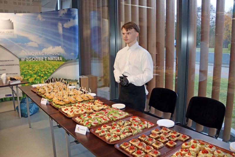 Mężczyzna odpowiedzialny za serwowanie przekąsek, stojący obok stołu z jedzeniem.