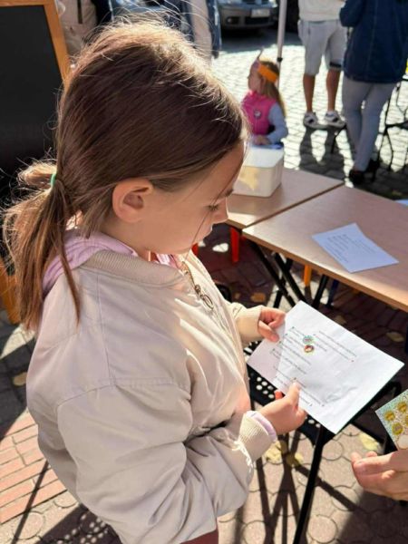 zdjęcie przedstawia dziewczynkę przy stoisku promującym projekt. zdjęcie przedstawia dziewczynkę przy stoisku promującym projekt.