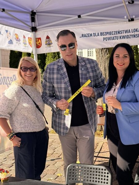 zdjęcie przedstawia trzy osoby, w tym Burmistrza Miasta Kwidzyna promujących gadżety promocyjne projekt. 