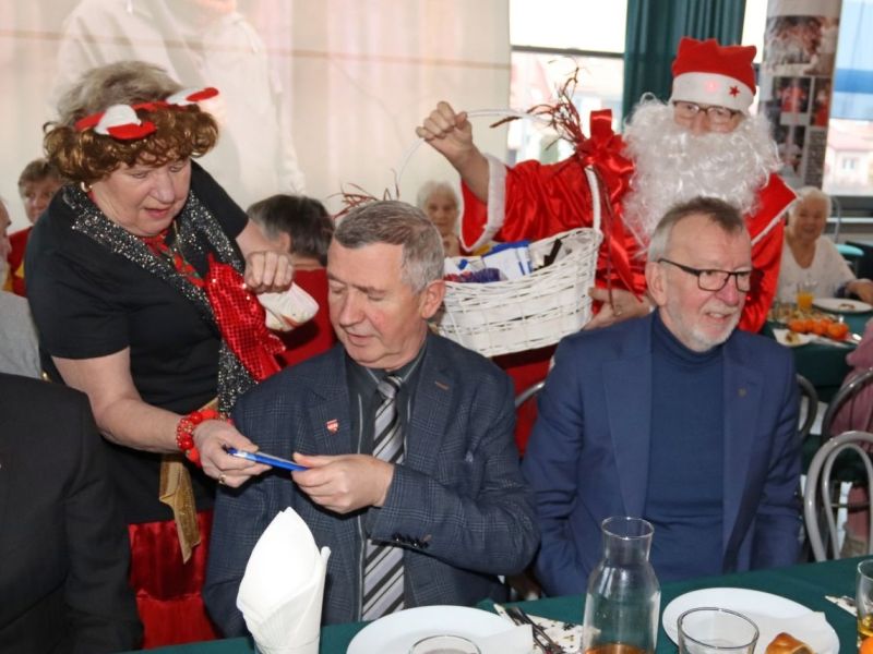  Dwoje organizatorów w świątecznych strojach wręcza słodkie upominki Ludwikowi Butkiewiczowi, Wicestaroście Sztumskiemu, oraz Andrzejowi Krzysztofiakowi, Przewodniczącemu Rady Miejskiej w Kwidzynie.