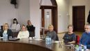 zdjęcie przedstawia grupę osób siedzących przy okrągłym stole podczas spotkania