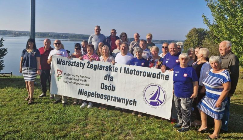 Wszyscy członkowie Pomorskiego Stowarzyszenia Żeglarzy Niepełnosprawnych pozują do zdjęcia.