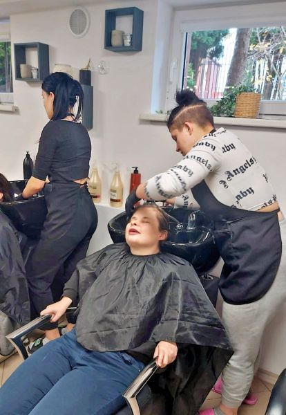 Wychowanki Młodzieżowego Ośrodka Wychowawczego im. Janusza Korczaka w Kwidzynie myją głowę osobie z niepełnosprawnością w pracowni fryzjerskiej