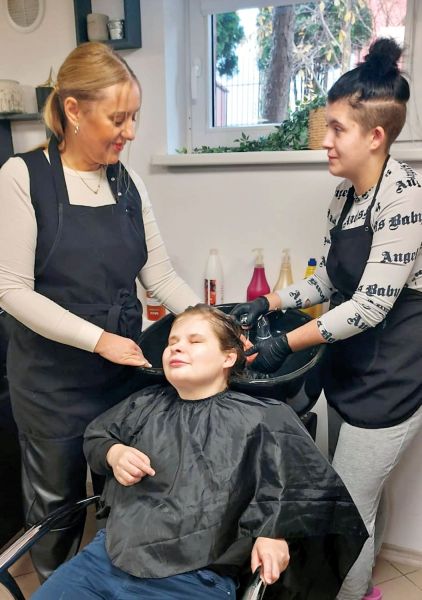 Wychowanki Młodzieżowego Ośrodka Wychowawczego im. Janusza Korczaka w Kwidzynie myją głowę osobie z niepełnosprawnością w pracowni fryzjerskiej