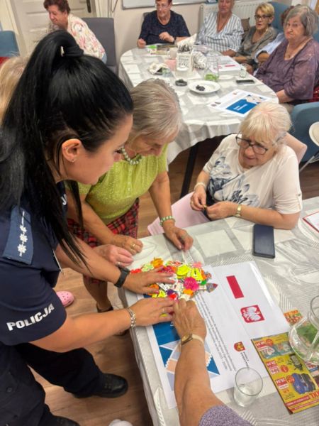 zdjęcie przedstawia policjantkę pokazującą odblaski starszym osobom. 
