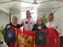 Para taneczna Monika i Mariusz Budyś w strojach reprezentacji narodowej oraz dwie inne osoby prezentują flagę powiatu kwidzyńskiego w namiocie startowym podczas Mistrzostw Świata w Vagos