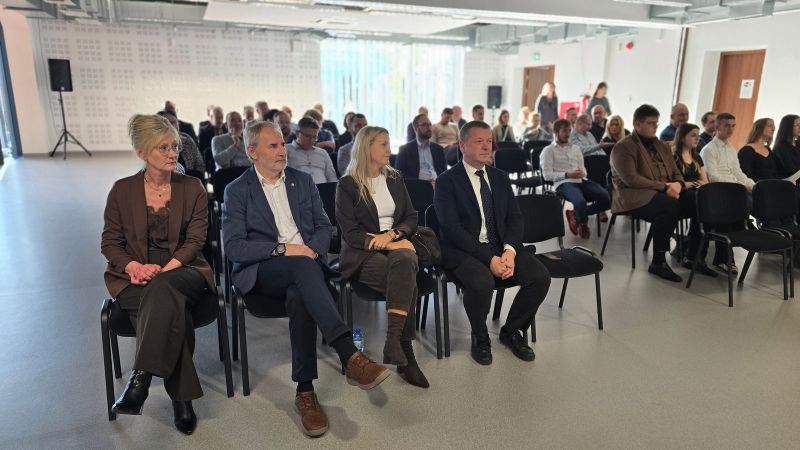  Na zdjęciu widać grupę ludzi siedzących w sali audytoryjnej