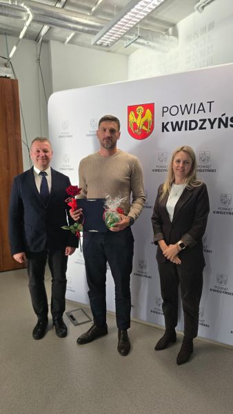 Na zdjęciu widać starostę kwidzyńskiego, kobietę i mężczyznę pozujących na tle ścianki powiatu kwidzyńskiego Na zdjęciu widać starostę kwidzyńskiego, kobietę i mężczyznę pozujących na tle ścianki powiatu kwidzyńskiego