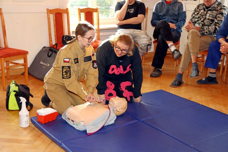 Strażaczka str. Wiktoria Jerzyk uczy uczestniczkę Warsztatu Terapii Zajęciowej w Górkach resuscytacji krążeniowo-oddechowej na manekinie.