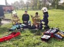 Czterech strażaków podczas szkolenia udziela pomocy symulowanej osobie rannej.