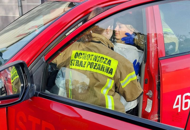 Strażaczka podczas akcji ratunkowej zabezpiecza osobą poszkodowaną w samochodzie osobowym