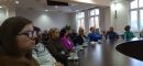 Druga grupa osób uczestnicząca w szkoleniu na miejscach siedzących przy okrągłym stole konferencyjnym oraz w tylnej części sali