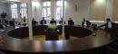 Trzecia grupa szkoleniowa uczestnicząca w szkoleniu na miejscach siedzących przy okrągłym stole konferencyjnym wraz z osobą prowadzącą szkolenie omawiającą szczegółowe tematy szkolenia