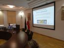 Osoba prowadząca szkolenie przy stole konferencyjnym omawiająca szczegółowe tematy objęte szkoleniem