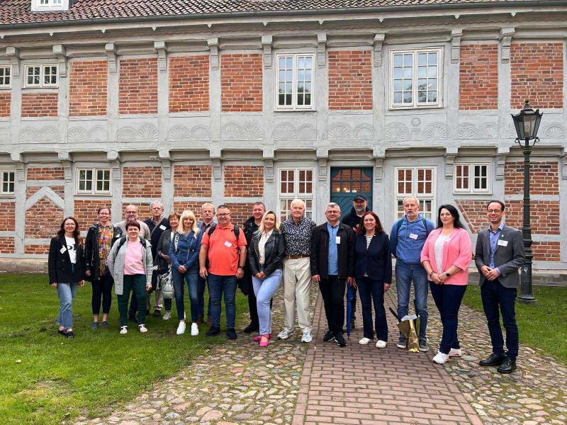 Zdjęcie 4 przedstawia przedstawicieli Powiatu Kwidzyńskiego i Powiatu Osterholz stojących na tle budynku.